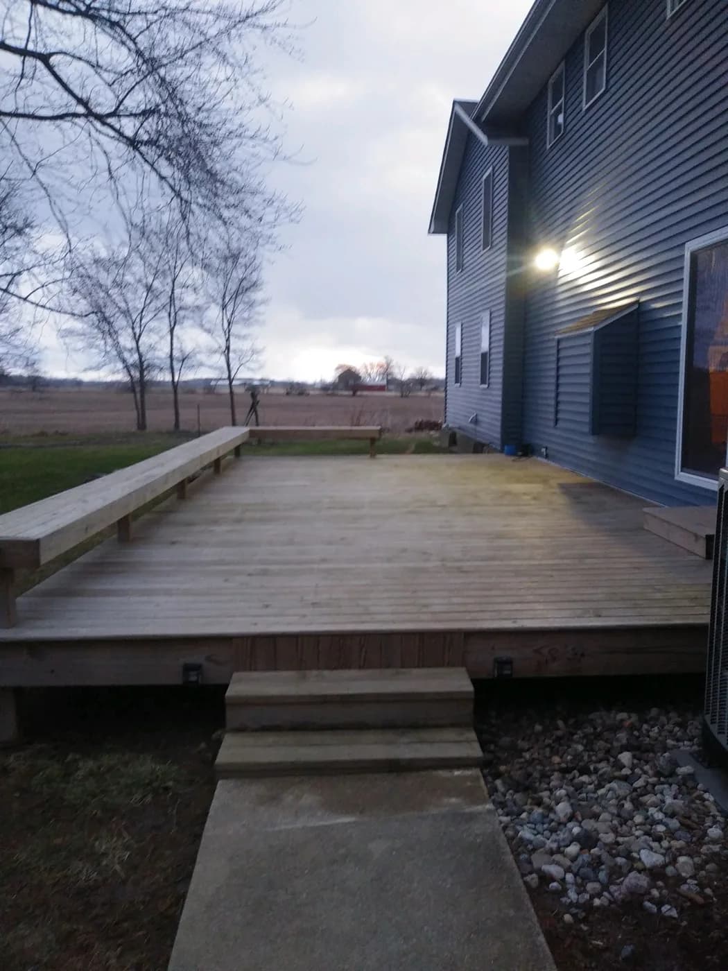 Large wood deck with built-in bench seating at evening